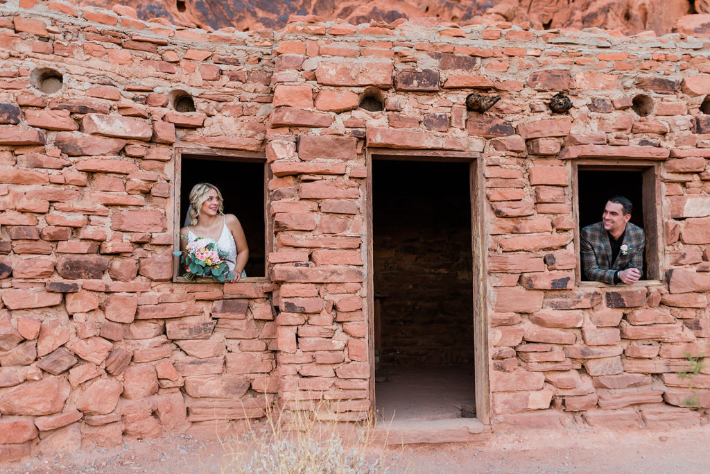 bride and groom looking out a window of a brick cabin during their elopement