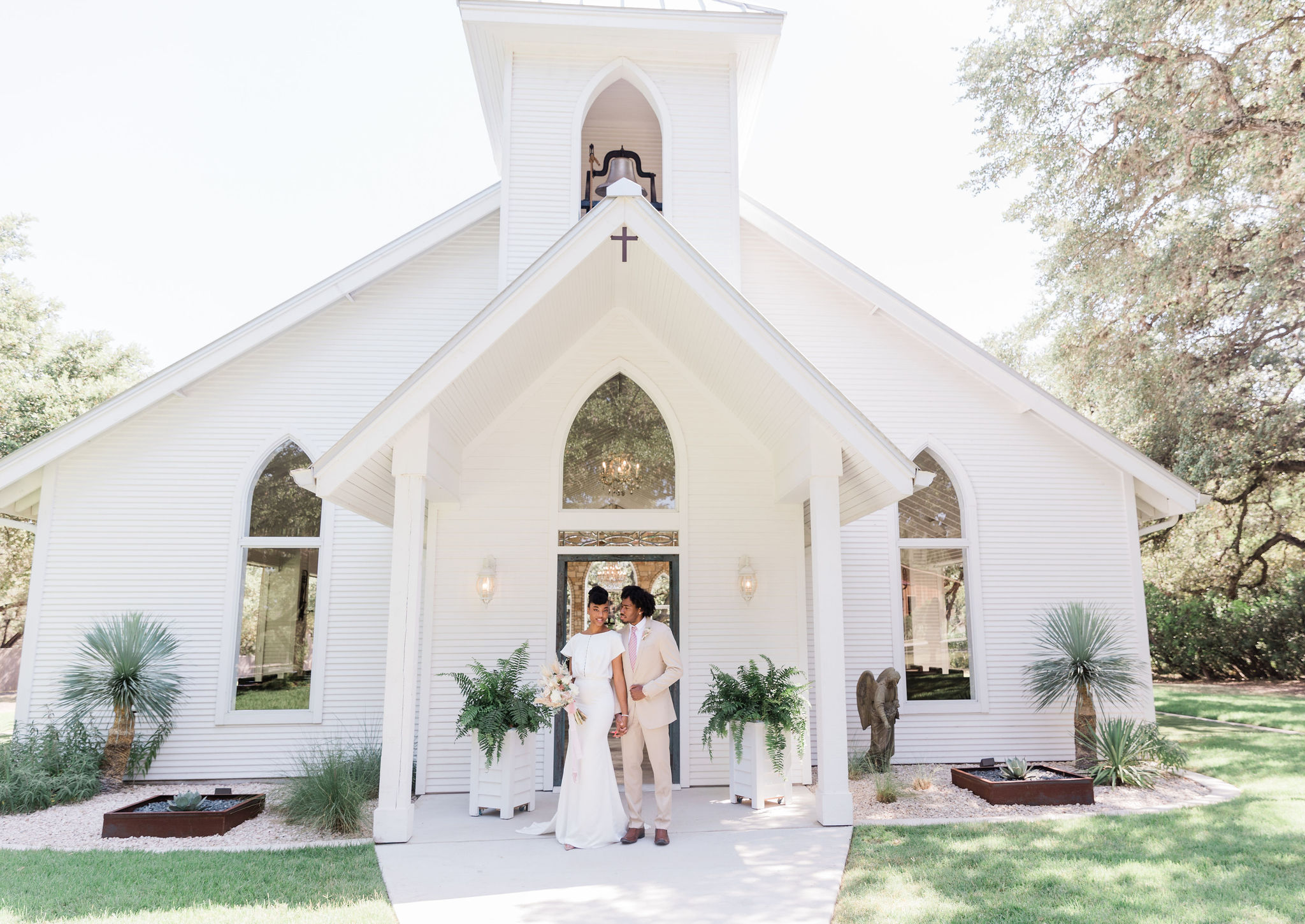 The couple standing in front of the chapel as newlyweds