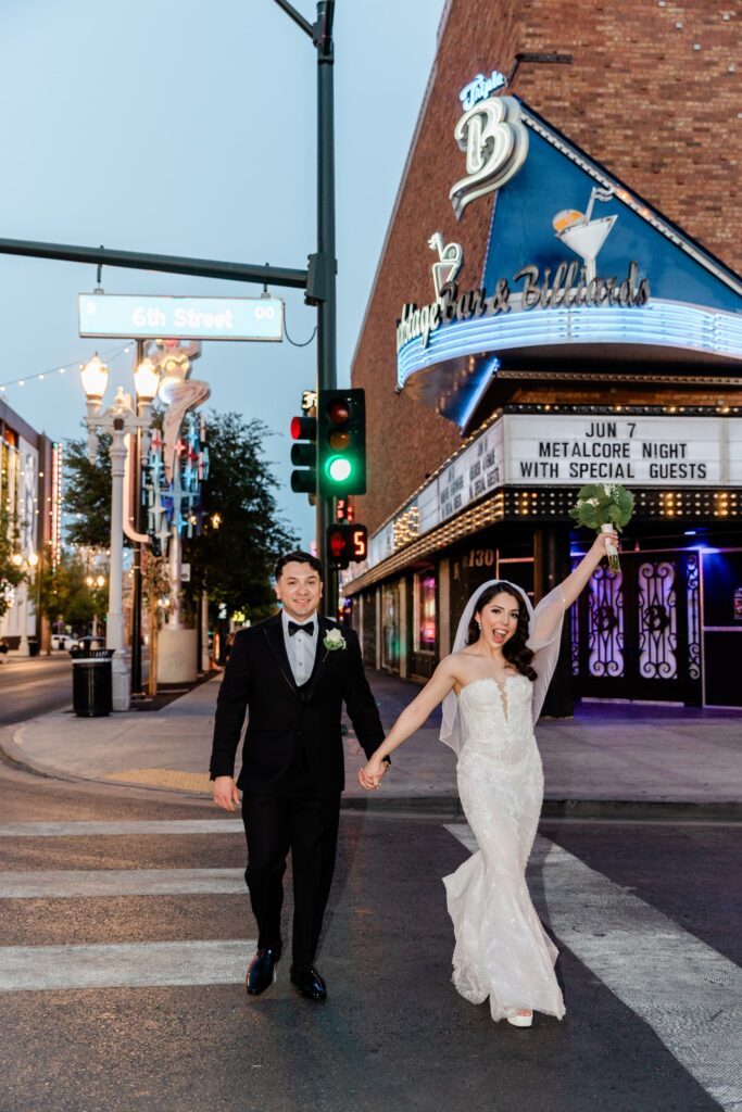 Newlyweds walking down Fremont Street while holding her bouquet up in the air